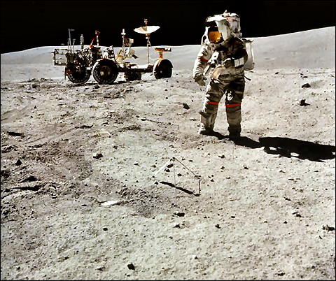 Astronaut John Young, shown with a sample bag in his left hand, moves toward the bottom part of the gnomon (center) while collecting samples at the North Ray Crater geological site. 