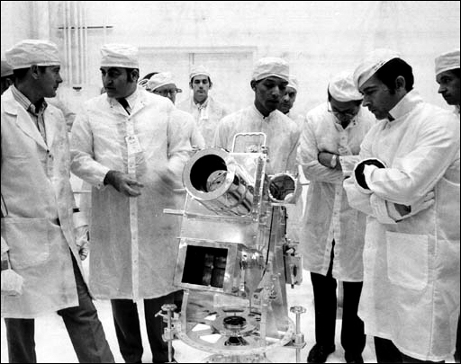 Top: Dr. George R. Carruthers, center, principle investigator for the lunar surface far-ultraviolet camera, discusses the instrument with Apollo 16 Commander John Young, right, and Apollo Program Director Rocco Petrone, left. Talking with Petrone is Apollo 16 Lunar Module Pilot Charlie Duke.
